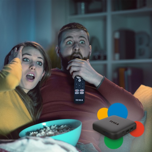 Žena s mužem u televize s popcornem sledující obsah z TESLA MediaBox XA400 Android TV.